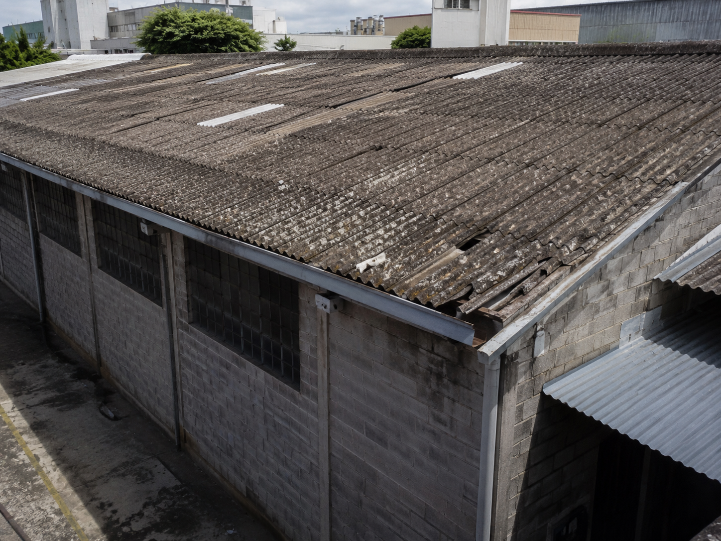 Barracão com telhado antigo de fibrocimento desgastado antes da reforma